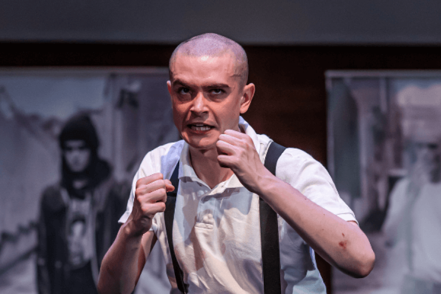 A still from Lyric production 'Blackout' featuring a close up of a young man with his fists raised in front of his chest.